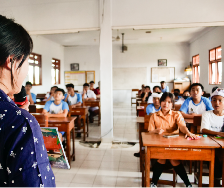 A group of students sitting in the classroom as they watch and listen to their teacher